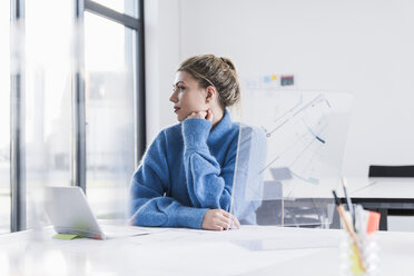 Young woman with laptop and transparent design at desk in office thinking - UUF12849