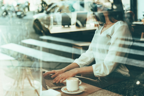 Lachende Geschäftsfrau mit Laptop in einem Café, lizenzfreies Stockfoto