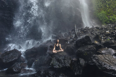 Indonesien, Bali, junge Frau übt Yoga am Sekumpul-Wasserfall - KNTF01035