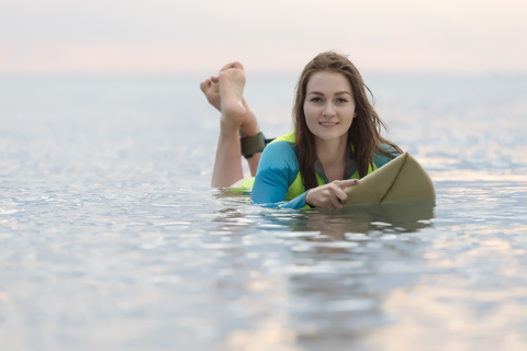 Indonesien, Bali, junge Frau auf Surfbrett liegend, lizenzfreies Stockfoto