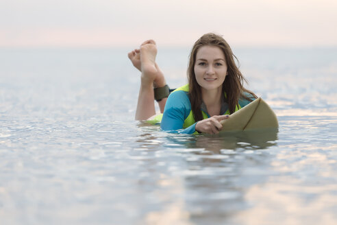 Indonesien, Bali, junge Frau auf Surfbrett liegend - KNTF01044