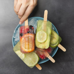 Woman's hand taking orange berry popsicle - SKCF00341