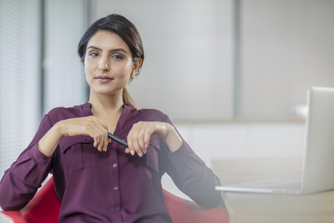 Porträt einer selbstbewussten Geschäftsfrau mit Laptop im Büro, lizenzfreies Stockfoto