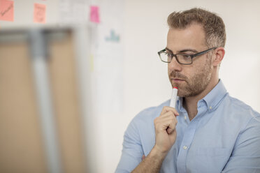 Businessman in front of board in office thinking - ZEF15041