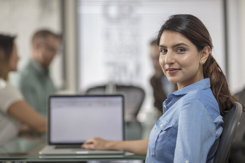 Porträt einer lächelnden Geschäftsfrau mit Laptop während einer Sitzung im Sitzungssaal eines Büros - ZEF15063