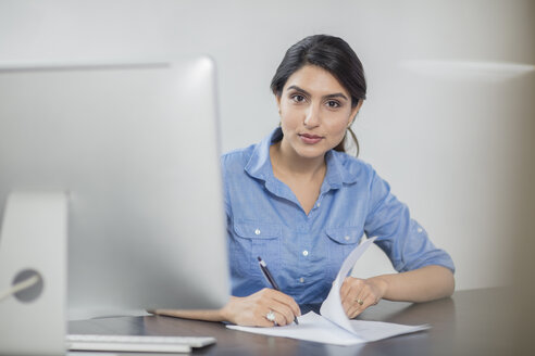 Porträt einer Geschäftsfrau, die sich am Schreibtisch im Büro Notizen macht - ZEF15069