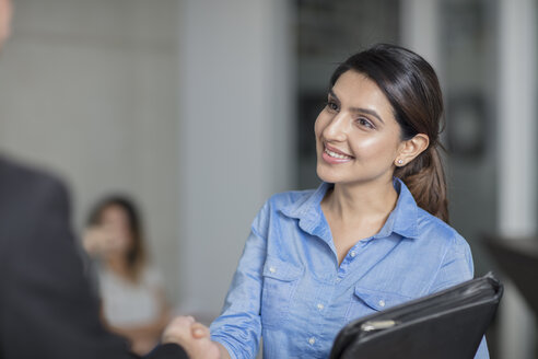 Smiling woman in office shaking hands - ZEF15074