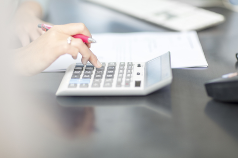 Woman at desk in office using calculator stock photo