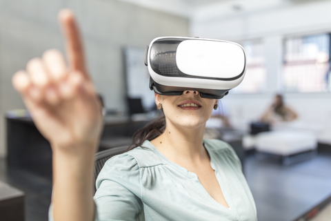 Frau mit VR-Brille im Büro, lizenzfreies Stockfoto