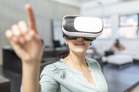 Woman wearing VR glasses in office stock photo