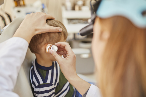 HNO-Arzt untersucht das Ohr eines Jungen, lizenzfreies Stockfoto