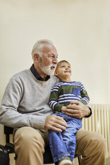 Boy sitting on grandfather's lap in waiting room - ZEDF01241