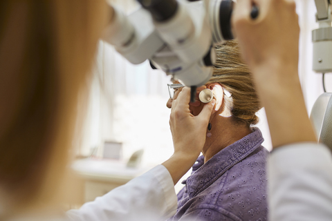 HNO-Arzt untersucht das Ohr einer älteren Frau, lizenzfreies Stockfoto