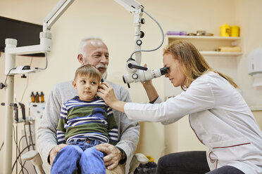 ENT physician examining ear of a boy sitting on grandfather's lap - ZEDF01244