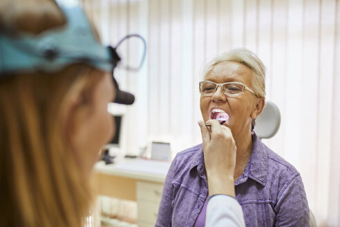 ENT physician examining mouth of a senior woman - ZEDF01248