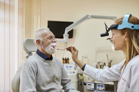 ENT physician examining mouth of a senior man stock photo