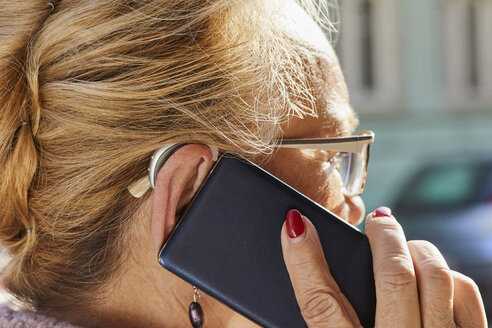 Close-up of senior woman with hearing aid using smartphone - ZEDF01255