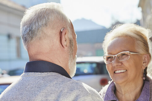 Close-up of senior man with hearing aid talking to senior woman - ZEDF01257