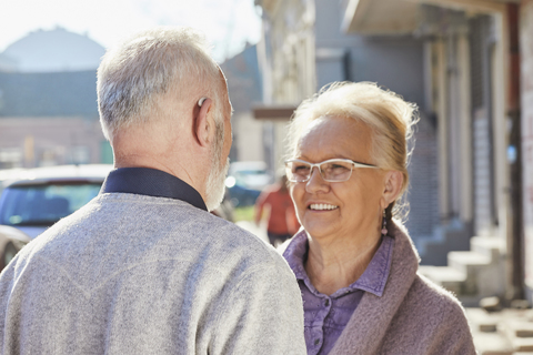 Nahaufnahme eines älteren Mannes mit Hörgerät im Gespräch mit einer älteren Frau, lizenzfreies Stockfoto