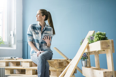 Woman refurbishing her new home with pallets, holding digital tablet - MOEF00870