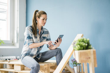 Frau renoviert ihr neues Haus mit Paletten und einem digitalen Tablet - MOEF00892