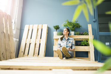 Beautiful woman taking a break from refurbishing her home with pallets, drinking coffee - MOEF00903