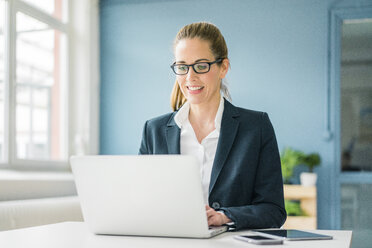 Businesswoman using laptop at home - MOEF00917