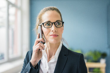 Successful businesswoman standing at home, talking on the phone - MOEF00920