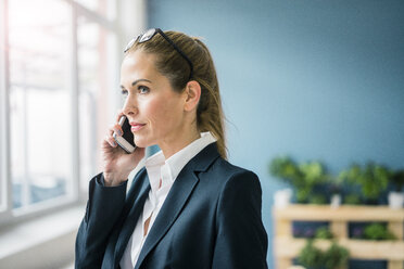 Successful businesswoman standing at home, talking on the phone - MOEF00924