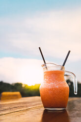 Thailand, carafe with refreshing drink on table at sunset - KKAF00879