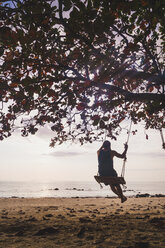 Thailand, Phi Phi Islands, Ko Phi Phi, man on tree swing on the beach - KKAF00892