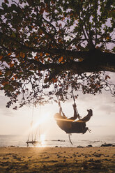Thailand, Phi Phi Islands, Ko Phi Phi, man on tree swing on the beach in backlight - KKAF00893