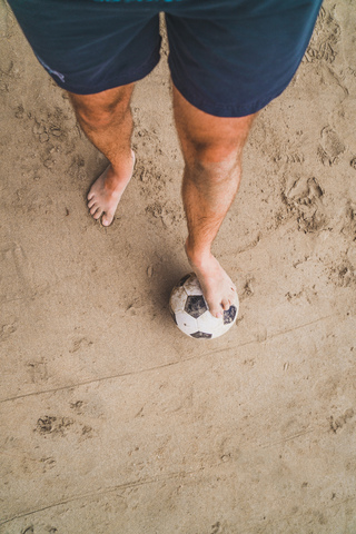 Low section of man with footall on the beach stock photo