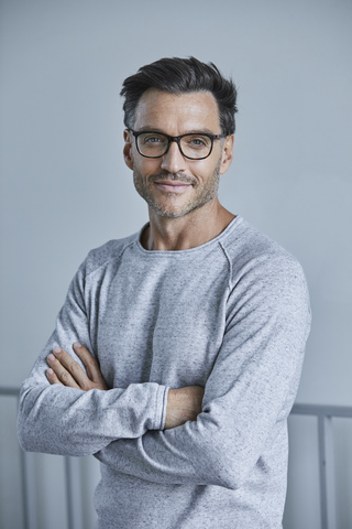 Porträt eines lächelnden Mannes mit Bartstoppeln, grauem Sweatshirt und Brille, lizenzfreies Stockfoto