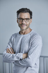 Portrait of smiling man with stubble wearing grey sweatshirt and glasses - PNEF00547