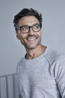 Portrait of laughing man with stubble wearing grey sweatshirt and glasses - PNEF00548
