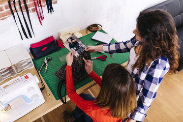 Two fashion designers in studio looking at photography - JRFF01576