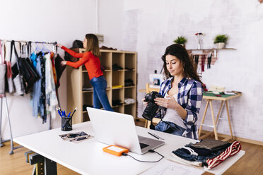 Fashion designer with camera and laptop in studio - JRFF01579