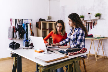 Zwei Modedesigner mit Laptop im Atelier machen sich Notizen - JRFF01582