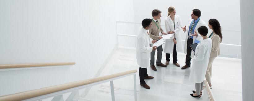 Geschäftsleute und Ärzte treffen sich auf einem Treppenabsatz - CAIF00014