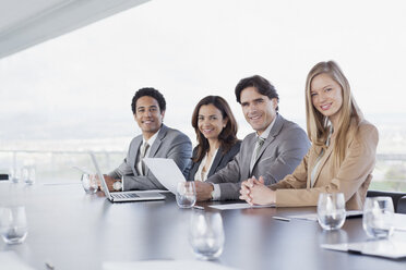 Porträt von lächelnden Geschäftsleuten, die in einer Reihe im Konferenzraum sitzen - CAIF00026
