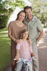 Portrait of smiling parents with daughter on bicycle - CAIF00050