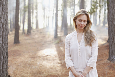 Porträt einer heiteren Frau in einem sonnigen Wald - CAIF00051