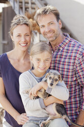 Portrait of smiling family holding puppy - CAIF00052