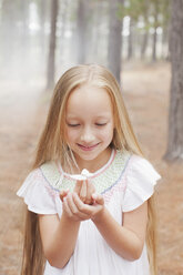 Close up of girl holding butterfly in woods - CAIF00059