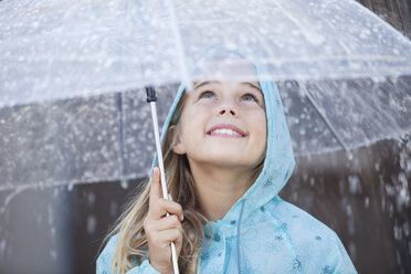 Nahaufnahme eines lächelnden Mädchens unter einem Regenschirm bei strömendem Regen - CAIF00064