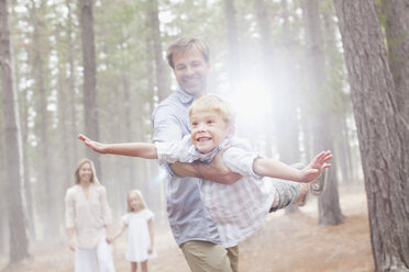 Vater fliegt Sohn im sonnigen Wald - CAIF00065