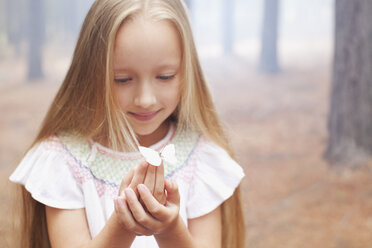 Close up of girl holding butterfly in woods - CAIF00067