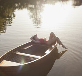Gelassene Frau beim Sonnenbaden im Boot auf dem See - CAIF00082