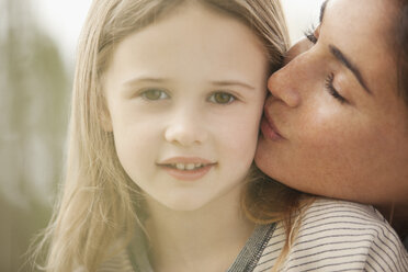 Close up portrait of mother kissing daughter’s cheek - CAIF00092